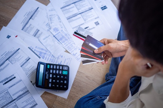 A person with credit cards and a pile of documents and calculator