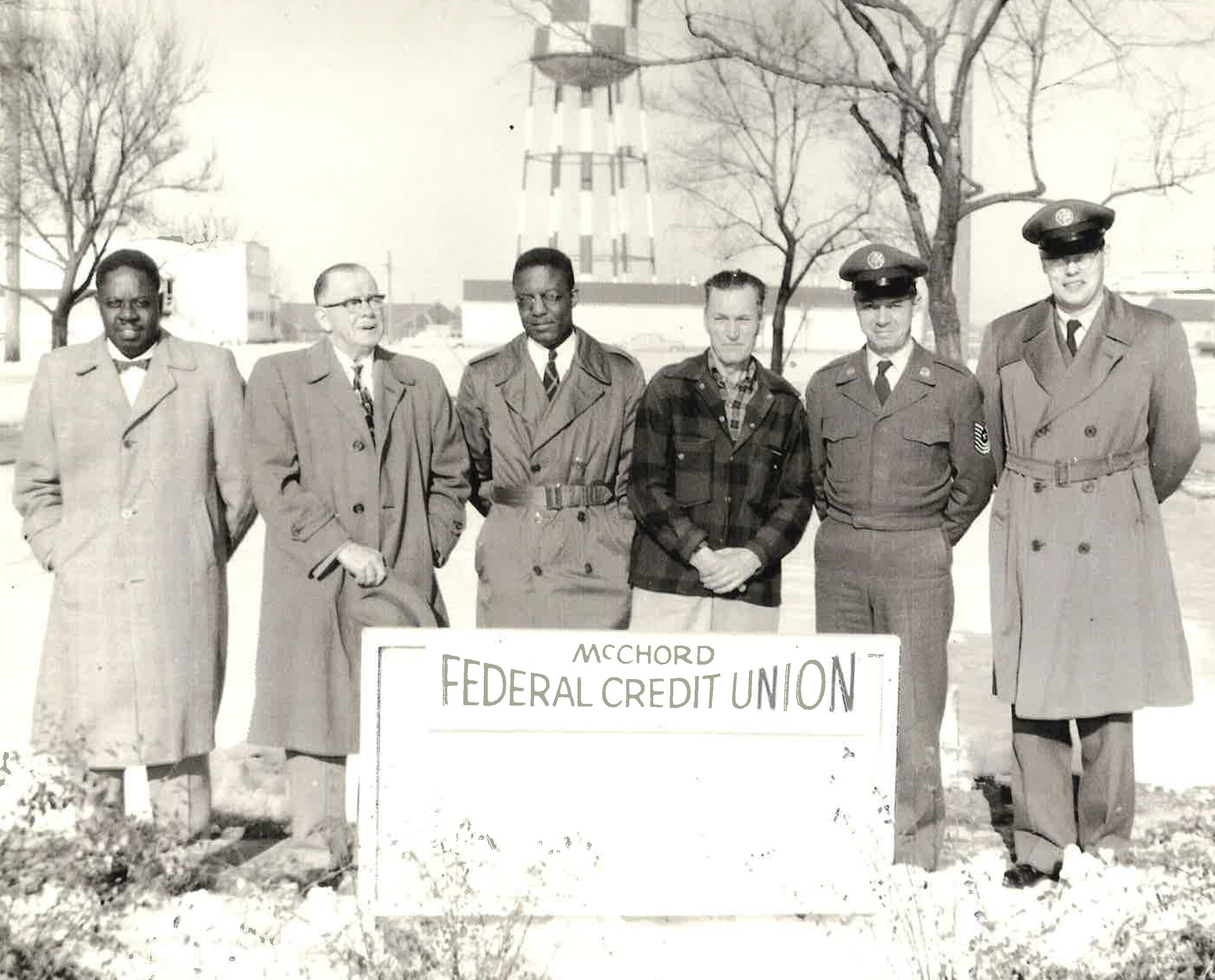Group of men standing in front of McChord Federal Credit Union sign